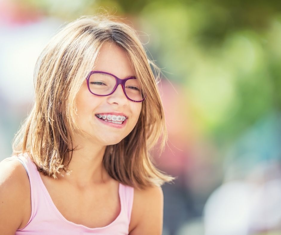 Bambina sorridente con apparecchio per l'ortodonzia preventiva
